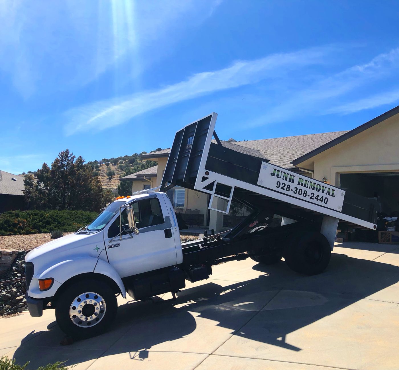 True West Co. dump truck raising its bed to unload junk at an Arizona home